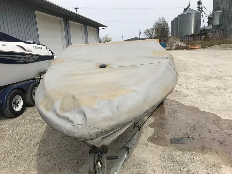 Slide: The Image of Covered 1987 Bayliner 1950 Capri boat on trailer, parked outdoors near industrial buildings. - 31