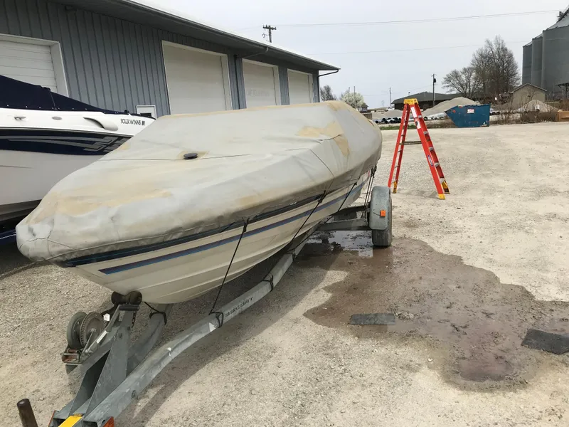 Slide: The Image of 1987 Bayliner 1950 Capri boat covered on trailer in outdoor storage area. - 32