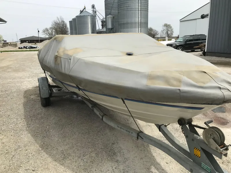 Slide: The Image of Covered 1987 Bayliner 1950 Capri boat on trailer, parked near industrial buildings. - 33