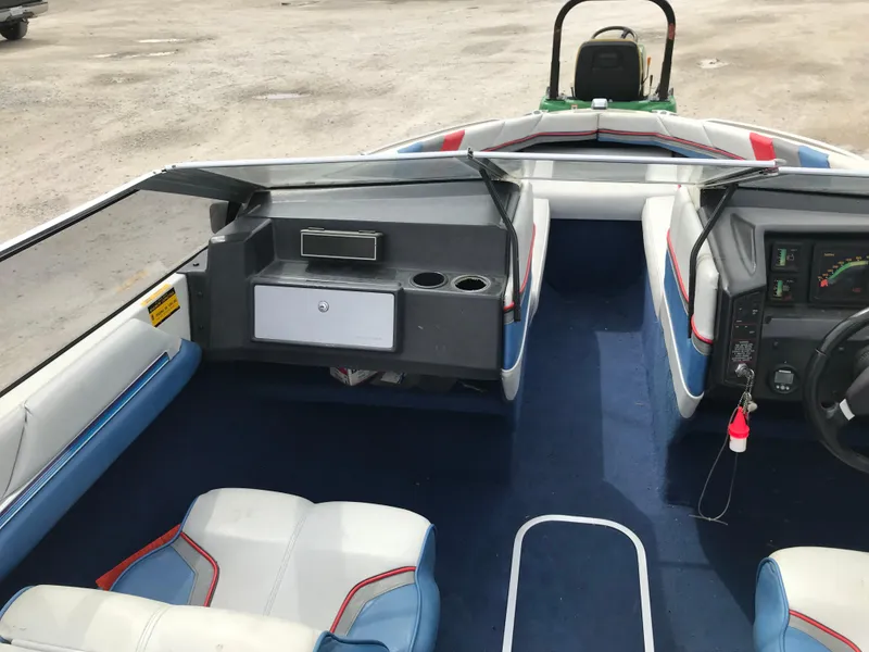 Slide: The Image of 1987 Bayliner 1950 Capri boat interior with blue and white seating, dashboard, and storage compartments. - 7