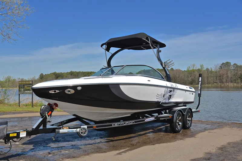 Slide: The Image of 2012 Centurion ELITE C4 boat on trailer by a lake, under clear blue sky. - 10