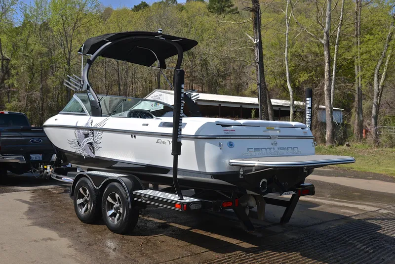 Slide: The Image of 2012 Centurion ELITE C4 boat on trailer, parked outdoors near trees. - 12