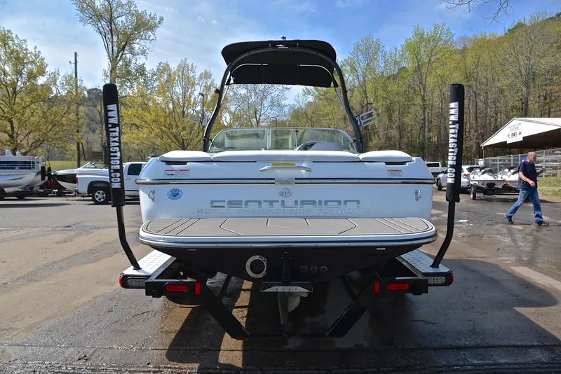 Slide: The Image of 2012 Centurion ELITE C4 boat, rear view, parked on a trailer in a wooded area. - 13