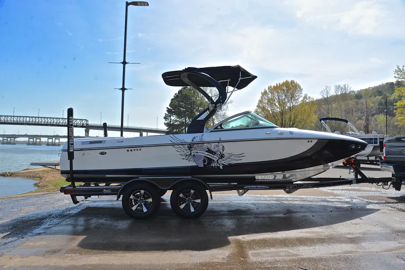 Slide: The Image of 2012 Centurion ELITE C4 boat on trailer by riverside, under clear sky. - 15