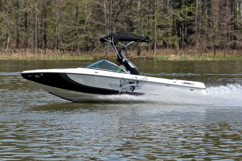 Slide: The Image of 2012 Centurion ELITE C4 speedboat cruising on a lake with forest backdrop. - 2