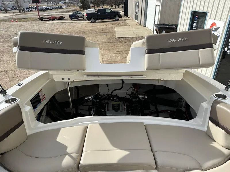 Slide: The Image of 2011 Sea Ray 250 SLX boat interior with open engine compartment, beige seating, and cup holders. - 28