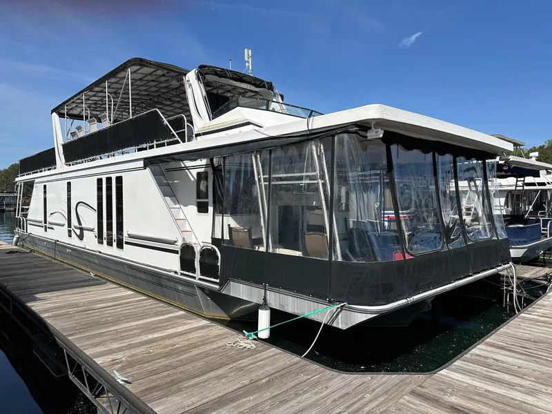 The Image of 2006 Lakeview 16x68 houseboat docked, featuring a covered upper deck and enclosed lower deck. - 0