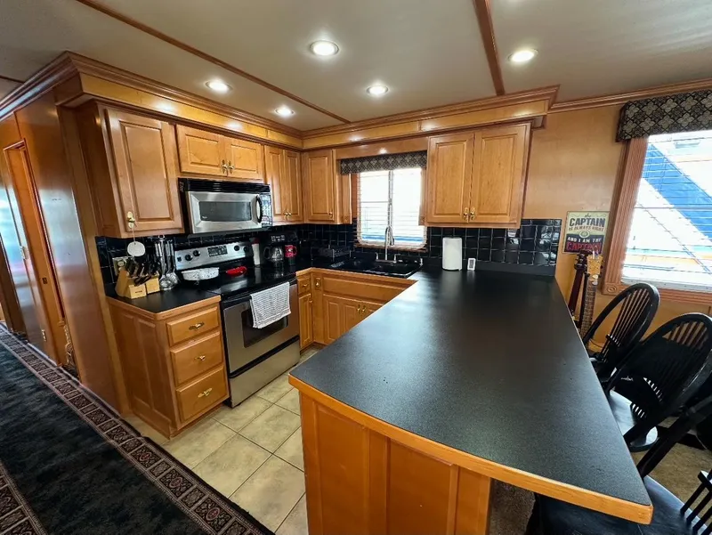 Slide: The Image of Modern kitchen in a 2006 Lakeview 16x68 houseboat with wooden cabinets and stainless steel appliances. - 4