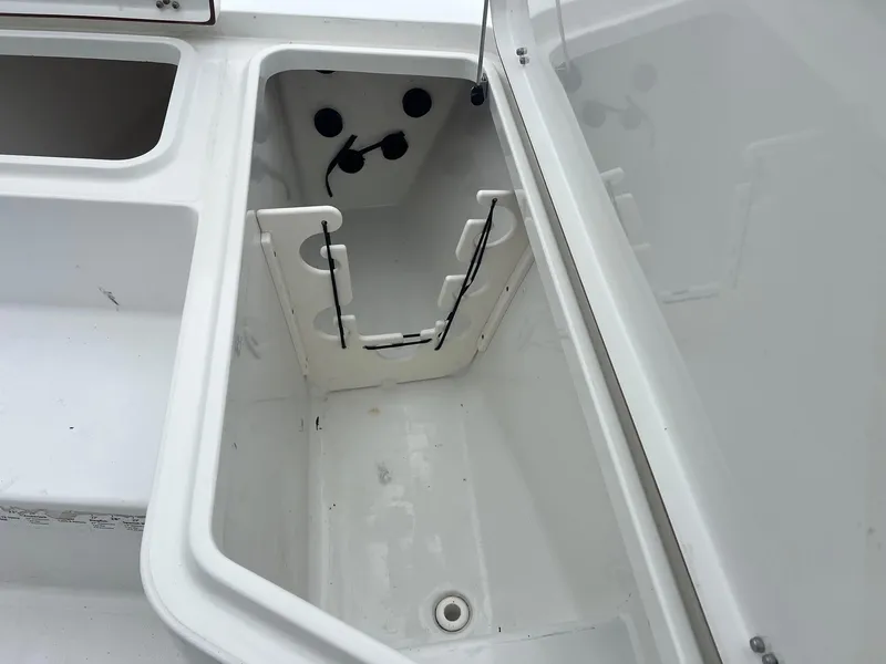 Slide: The Image of 2009 Sea Hunt BX24 boat storage compartment with rod holders and drainage. - 19