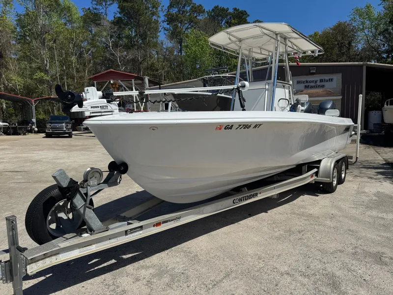 Slide: The Image of 2015 Contender 24 Sport boat on trailer, parked outdoors near trees and a building. - 1