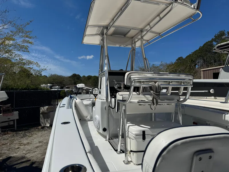 Slide: The Image of 2015 Contender 24 Sport boat with T-top and seating, docked outdoors under blue sky. - 28