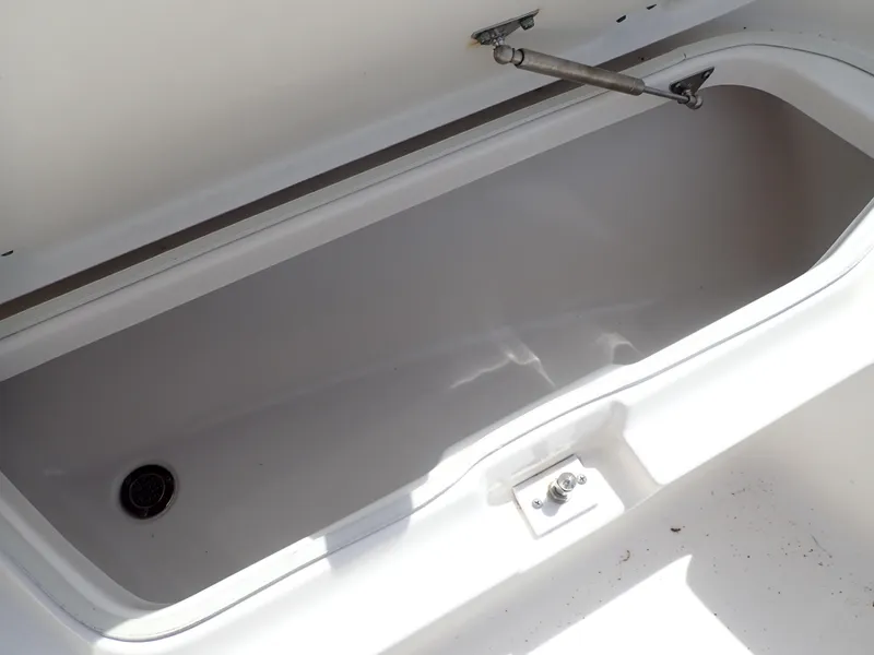 Slide: The Image of 2014 Robalo R200 Center Console storage compartment, open lid, white interior, drain plug visible. - 17