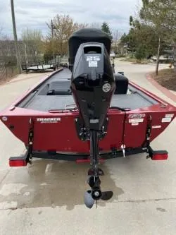 Slide: The Image of 2024 Tracker Pro 170 boat, red exterior, rear view with outboard motor, parked on a paved surface. - 4