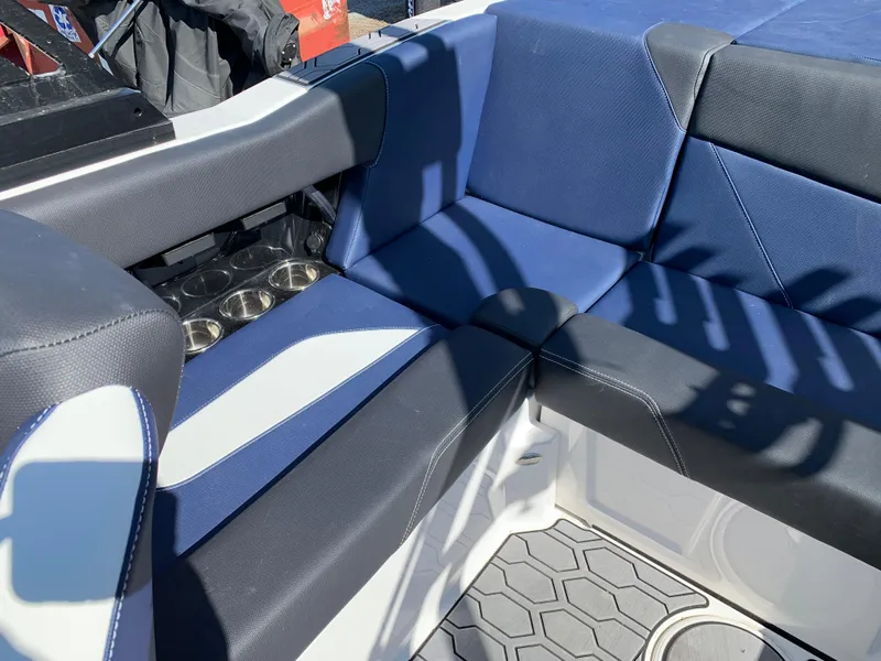 Slide: The Image of 2023 MasterCraft NXT20 interior with blue and black seating, cup holders, and textured flooring. - 17