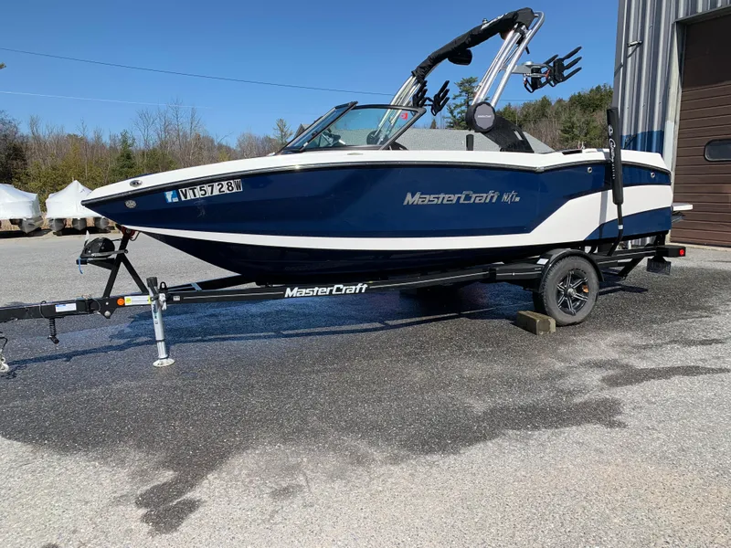 Slide: The Image of 2023 MasterCraft NXT20 boat on trailer, parked outdoors, showcasing sleek design and modern features. - 4