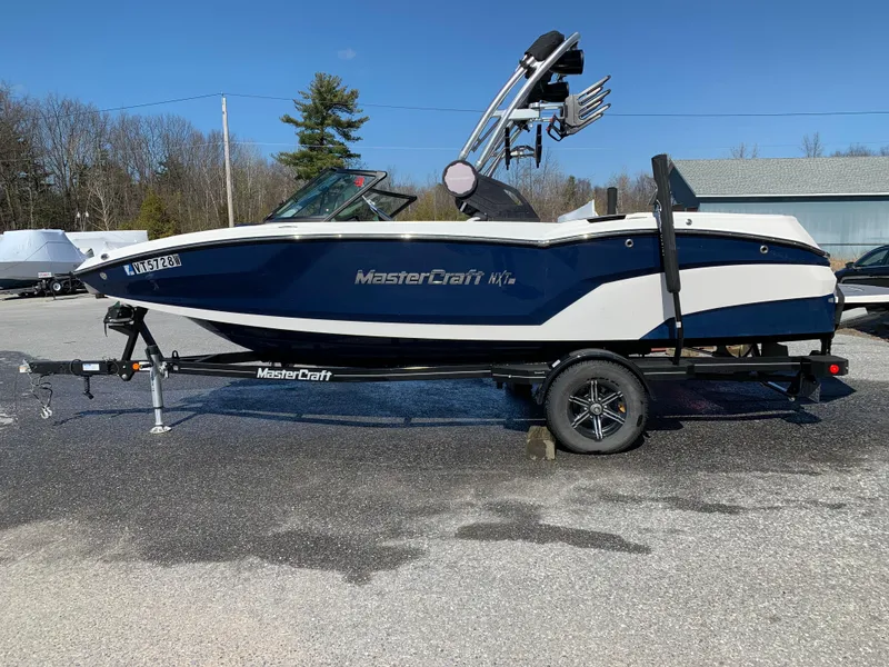 Slide: The Image of 2023 MasterCraft NXT20 boat on trailer, parked outdoors, side view. - 5