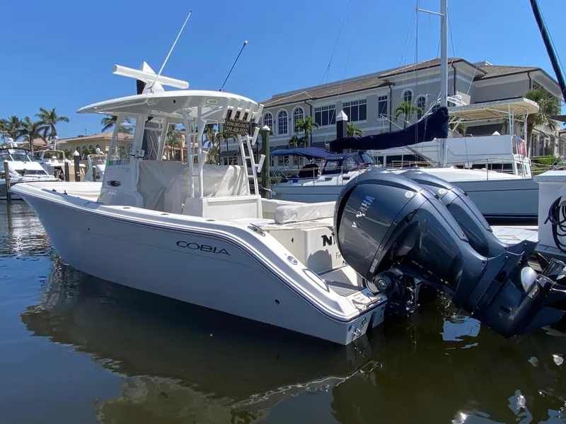 Slide: The Image of 2022 Cobia 301 Center Console boat docked at marina with clear blue sky. - 1