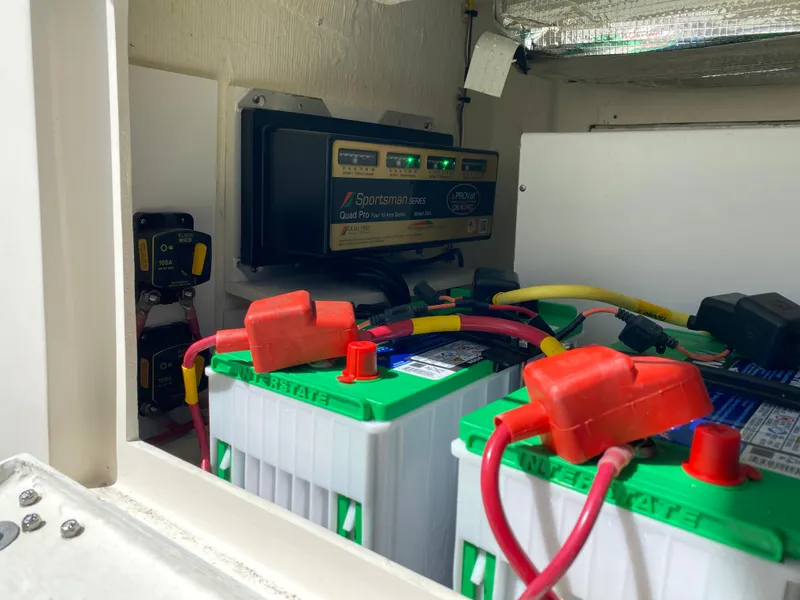 Slide: The Image of Battery compartment of a 2022 Cobia 301 Center Console boat with wiring and charger. - 10