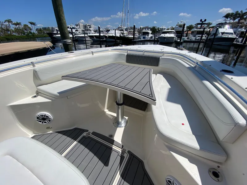 Slide: The Image of 2022 Cobia 301 Center Console boat interior with seating and table, docked at marina. - 17