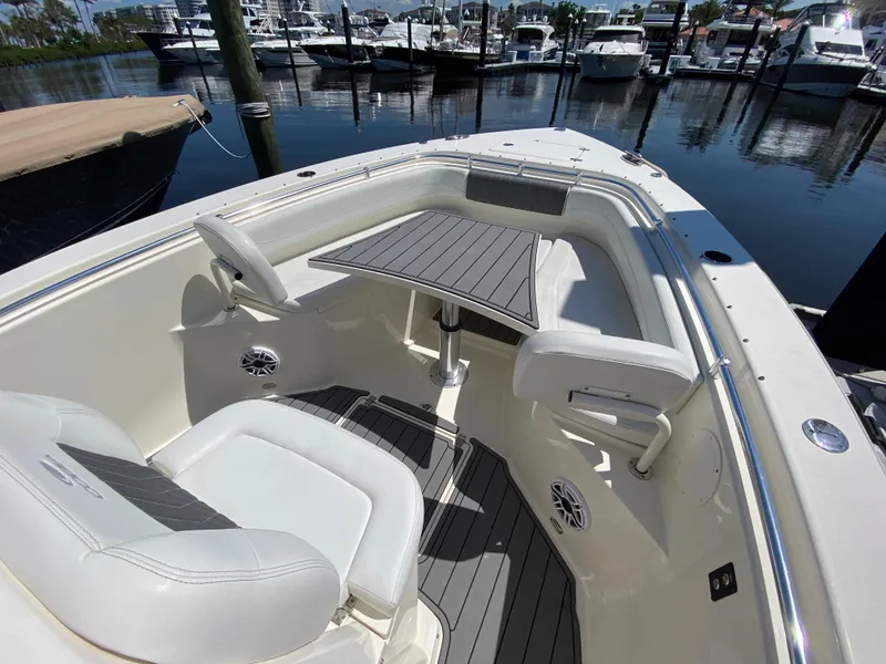 Slide: The Image of 2022 Cobia 301 Center Console boat interior with seating and table, docked at marina. - 18