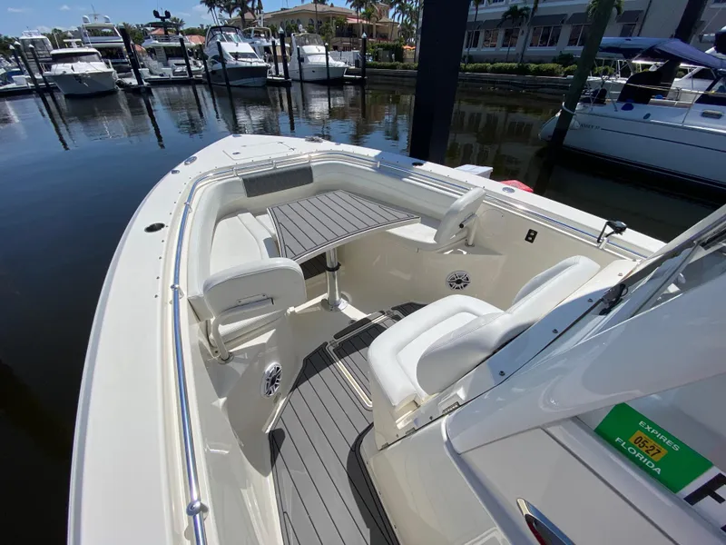 Slide: The Image of 2022 Cobia 301 Center Console boat docked at marina, featuring spacious seating and sleek design. - 19