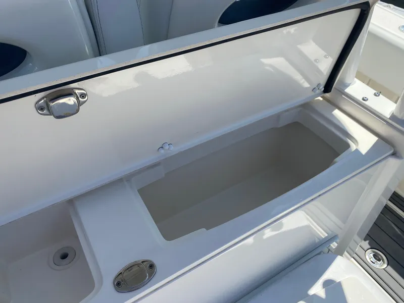 Slide: The Image of 2022 Cobia 301 Center Console storage compartment, open and empty, with stainless steel latch. - 26