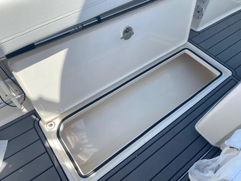 Slide: The Image of 2022 Cobia 301 Center Console storage compartment with open lid on deck. - 28