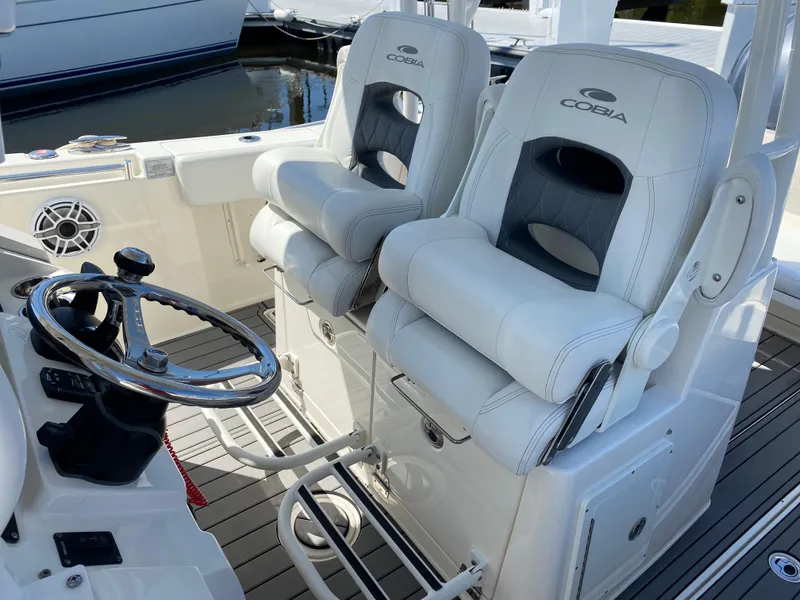 Slide: The Image of 2022 Cobia 301 Center Console boat with dual cushioned seats and steering wheel. - 6