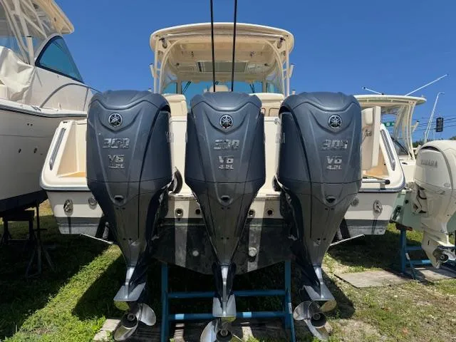 Slide: The Image of 2022 Grady-White Express 370 with triple Yamaha outboard engines, docked under clear blue sky. - 2