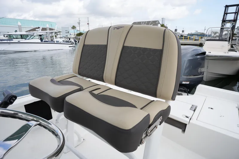 Slide: The Image of 2021 Tidewater 2210 Carolina Bay boat seats with beige and black upholstery at a marina. - 20