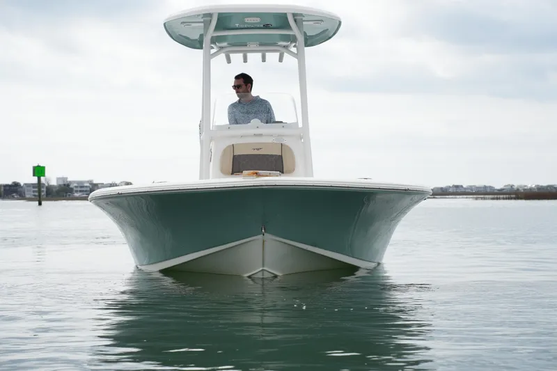 Slide: The Image of 2021 Tidewater 2210 Carolina Bay boat on calm water, with a person at the helm. - 8