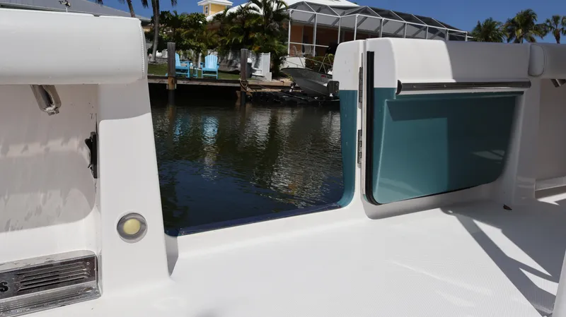 Slide: The Image of 2019 Everglades 435 Center Console boat with open side door, docked by water. - 18