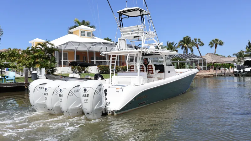 Slide: The Image of 2019 Everglades 435 Center Console boat with four engines, docked near a waterfront house. - 3