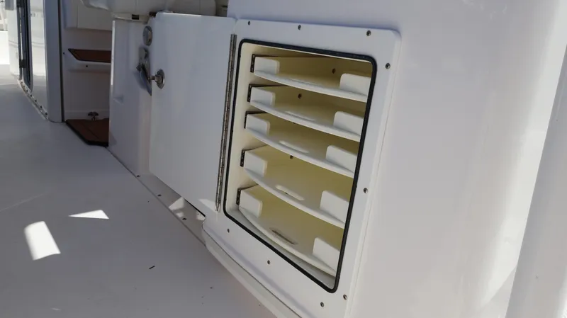 Slide: The Image of Storage compartment on 2019 Everglades 435 Center Console boat, featuring organized shelving. - 31
