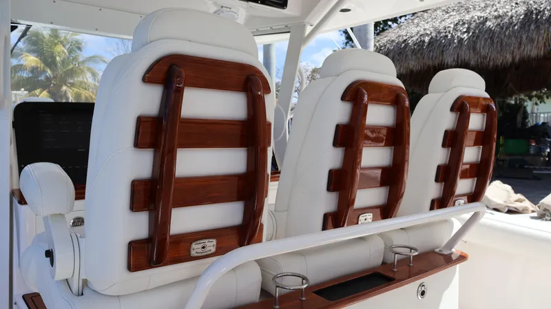 Slide: The Image of 2019 Everglades 435 Center Console boat seats with wooden accents and white upholstery. - 40