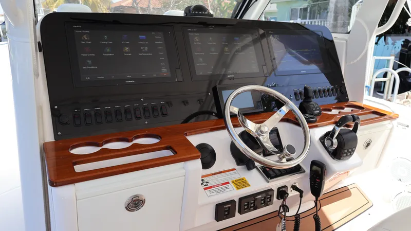 Slide: The Image of 2019 Everglades 435 Center Console boat dashboard with steering wheel and electronic controls. - 45