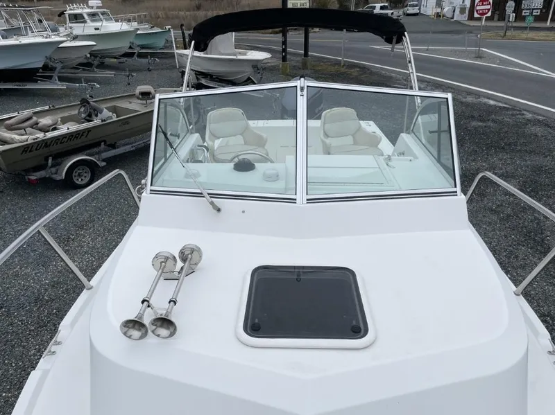 Slide: The Image of 2014 Parker 2310 Walkaround boat with windshield and seating, parked on gravel. - 10