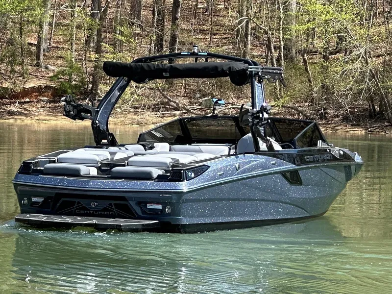 Slide: The Image of 2025 Centurion Fe23 boat on a serene lake with wooded background. - 1