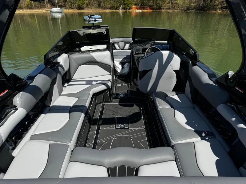 Slide: The Image of 2025 Centurion Fe23 boat interior with gray seating on a calm lake. - 11