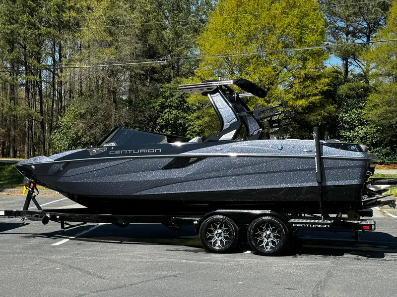 Slide: The Image of 2025 Centurion Fe23 boat on trailer, parked outdoors with trees in the background. - 21