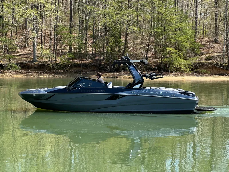 Slide: The Image of 2025 Centurion Fe23 boat on a calm lake with forested background. - 6