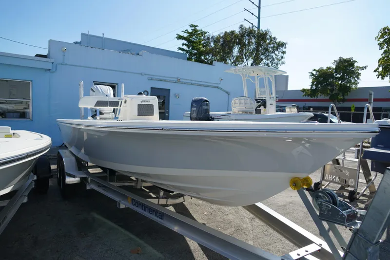 Slide: The Image of 2025 Hewes Redfisher 21 boat on trailer, parked outdoors near a blue building. - 21