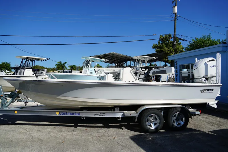 Slide: The Image of 2025 Hewes Redfisher 21 boat on trailer, parked outdoors under clear blue sky. - 6