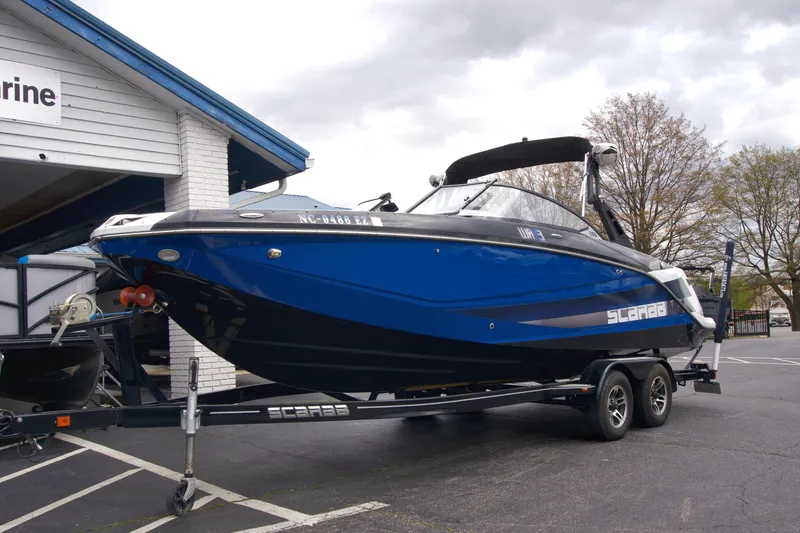 Slide: The Image of 2020 Scarab 255 ID boat on trailer, blue and black design, parked outside a building. - 3