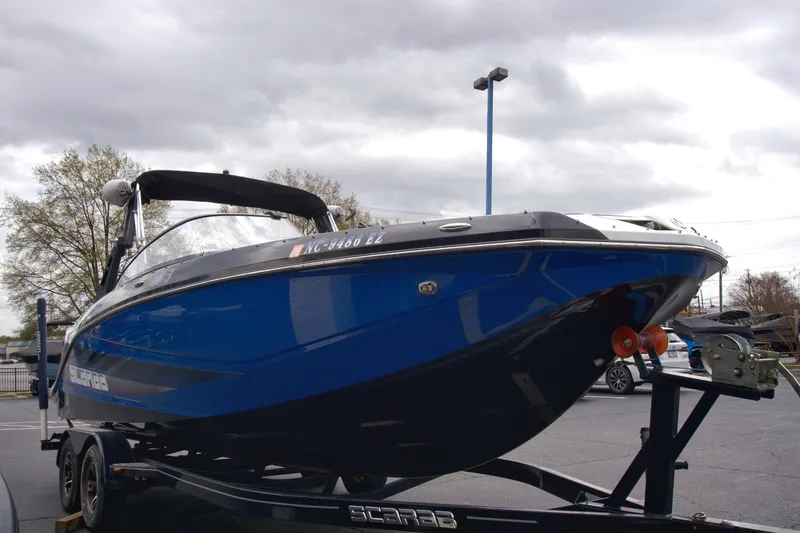 Slide: The Image of 2020 Scarab 255 ID boat on trailer, blue hull, overcast sky background. - 4