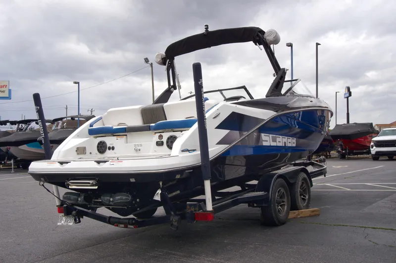 Slide: The Image of 2020 Scarab 255 ID boat on trailer, parked outdoors under cloudy sky. - 6