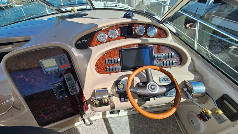 Slide: The Image of 2003 Sea Ray 410 Express Cruiser helm with wood accents and modern navigation controls. - 27