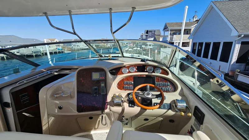 Slide: The Image of 2003 Sea Ray 410 Express Cruiser helm with waterfront view, featuring modern controls and wood accents. - 28