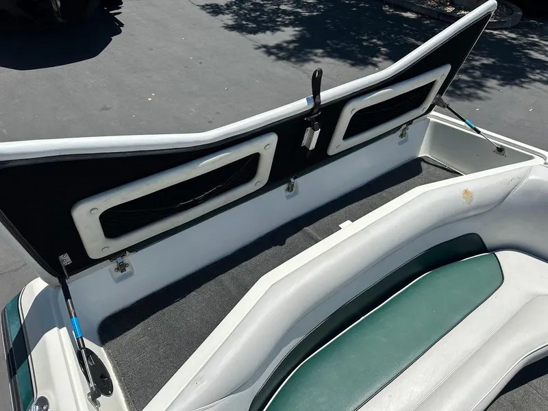 Slide: The Image of 1998 Ski Centurion sport bowrider interior with open storage compartment, featuring green and white seating. - 21