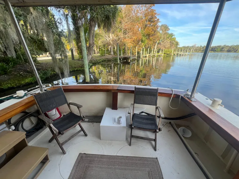 Slide: The Image of 1965 Romsdal Fjord boat deck with chairs, overlooking serene lake and lush trees. - 27